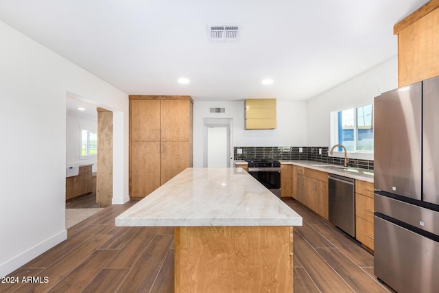 kitchen featuring backsplash, sink, dark hardwood / wood-style floors, a kitchen island, and stainless steel appliances