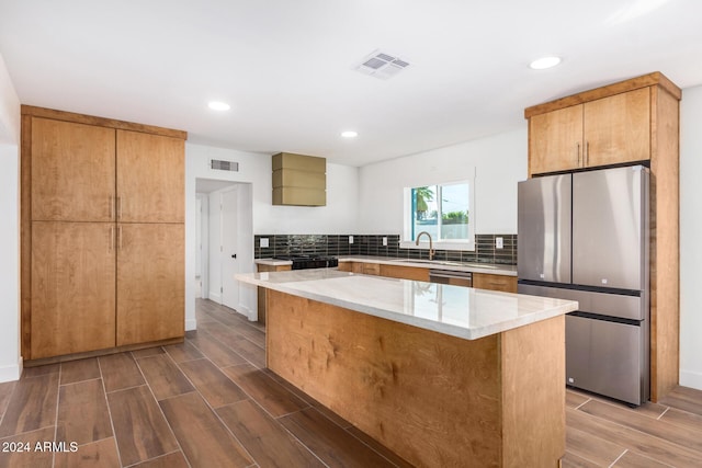 kitchen with hardwood / wood-style floors, a center island, stainless steel appliances, and backsplash