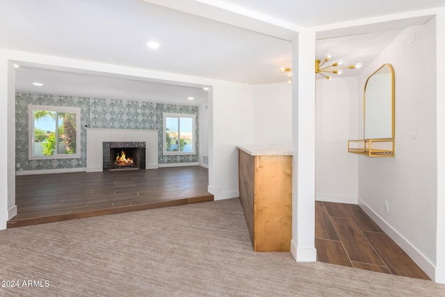 unfurnished living room with a chandelier, dark hardwood / wood-style flooring, and a tiled fireplace