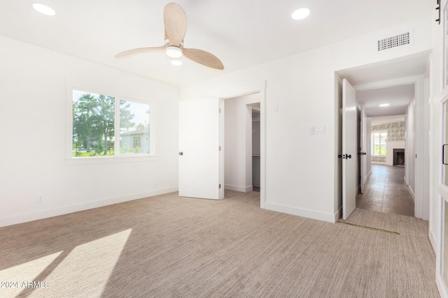 unfurnished bedroom featuring light carpet, a closet, and ceiling fan