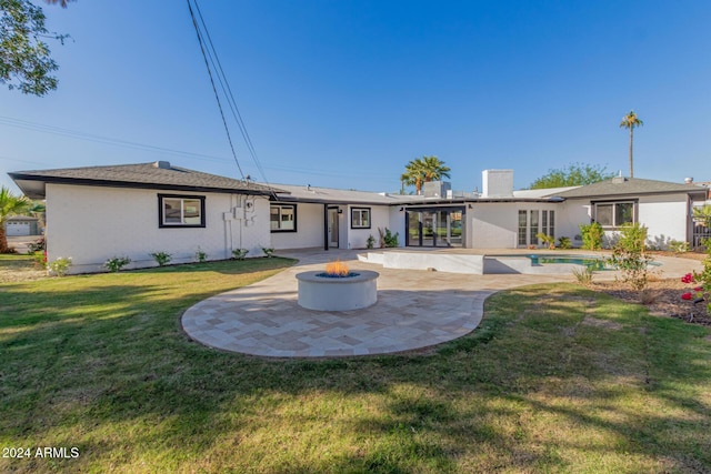 rear view of house with an outdoor fire pit, a patio area, and a lawn