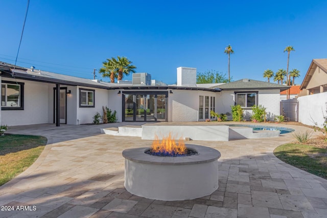 rear view of house with cooling unit, an outdoor fire pit, and a patio