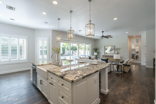 kitchen featuring ceiling fan with notable chandelier, an island with sink, dark hardwood / wood-style flooring, and white cabinetry