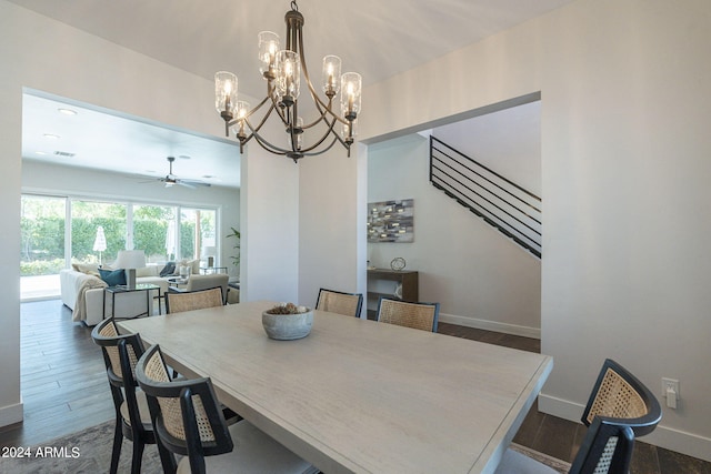 dining space featuring ceiling fan with notable chandelier and dark wood-type flooring