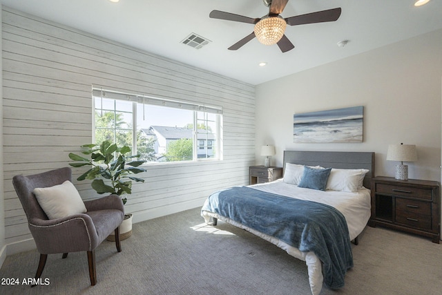 carpeted bedroom with ceiling fan and wood walls