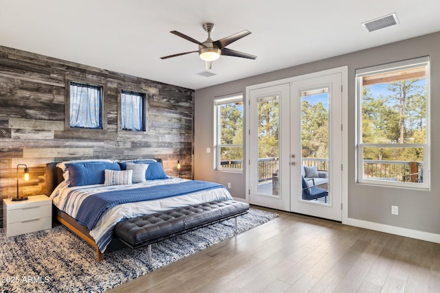 bedroom featuring multiple windows, access to outside, hardwood / wood-style floors, and french doors