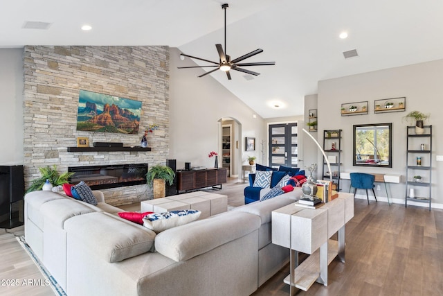 living room with wood-type flooring, high vaulted ceiling, ceiling fan, and a fireplace