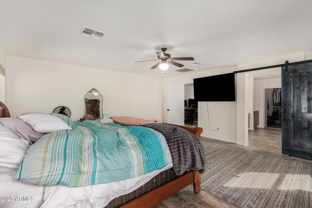 654 E Taylor Trl, San Tan Valley, AZ 85143 - bedroom featuring wood finished floors, a barn door, and a ceiling fan