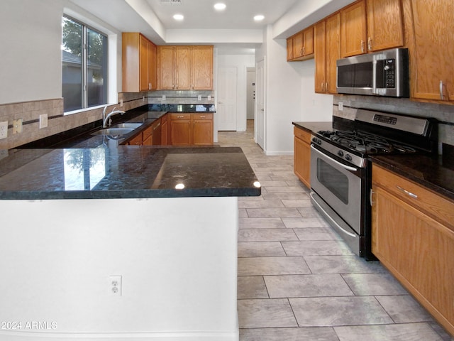 kitchen featuring sink, appliances with stainless steel finishes, kitchen peninsula, and decorative backsplash