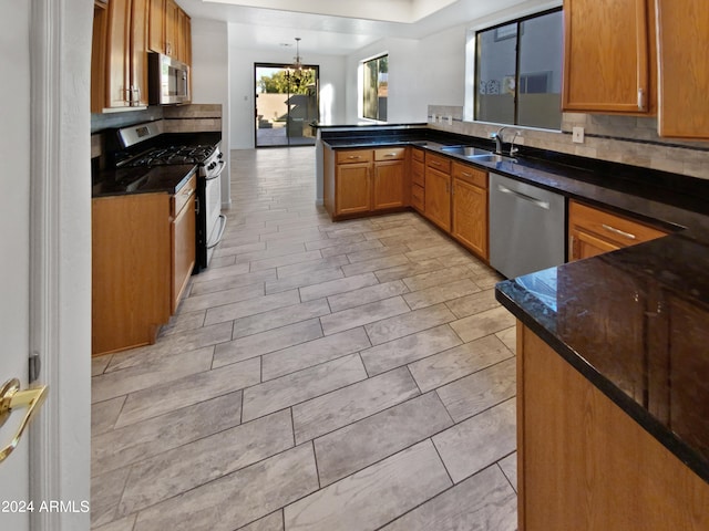 kitchen with kitchen peninsula, light hardwood / wood-style floors, decorative light fixtures, and appliances with stainless steel finishes