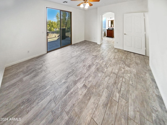 empty room with ceiling fan and light hardwood / wood-style flooring