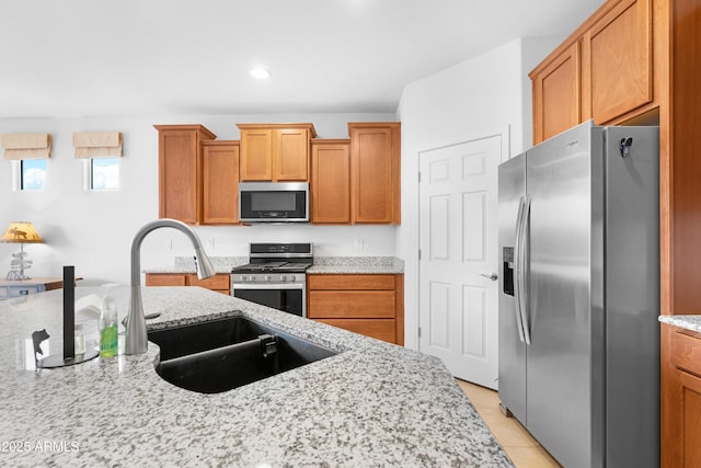 kitchen featuring sink, light stone countertops, stainless steel appliances, and light tile patterned floors