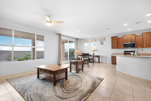 tiled living room with ceiling fan, sink, and a wealth of natural light