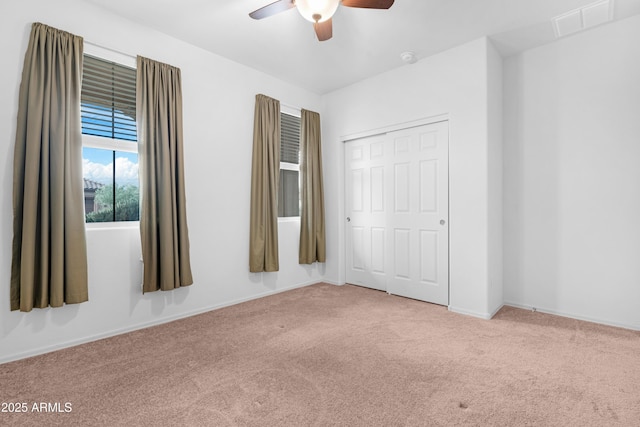 unfurnished bedroom with ceiling fan, light carpet, and a closet