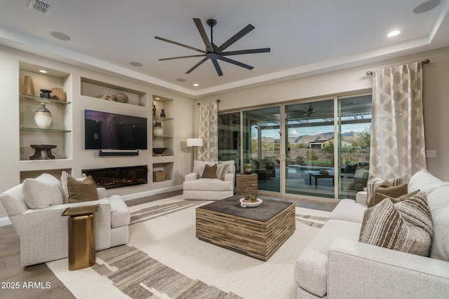 26673 W Ponderosa Ln, Buckeye, AZ 85396 - living room with visible vents, a glass covered fireplace, a ceiling fan, and wood finished floors