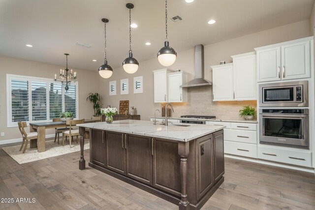 26673 W Ponderosa Ln, Buckeye, AZ 85396 - kitchen with an inviting chandelier, a sink, visible vents, appliances with stainless steel finishes, and wall chimney exhaust hood
