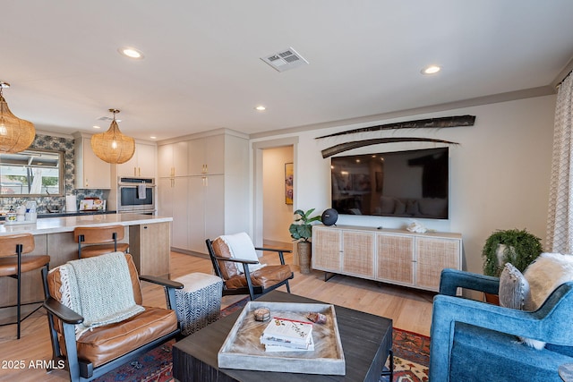 living room with recessed lighting, visible vents, and light wood-type flooring