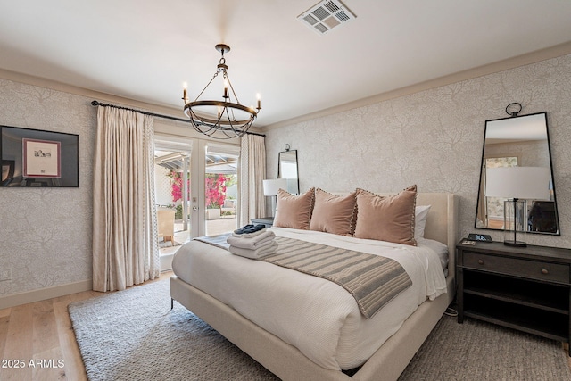 bedroom with baseboards, visible vents, a notable chandelier, wood finished floors, and access to outside