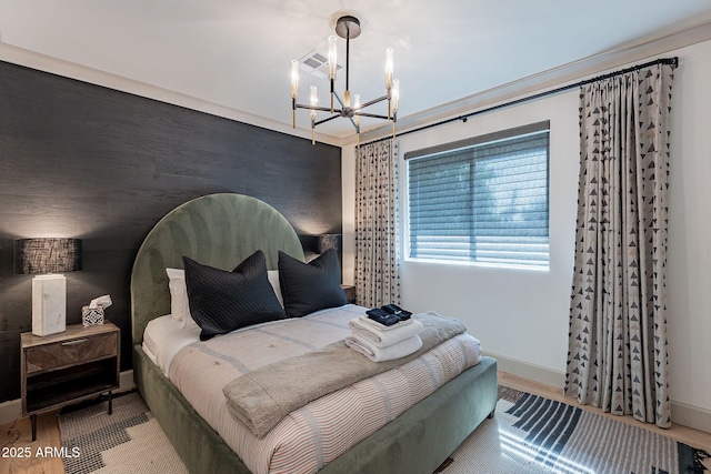 bedroom with baseboards, wood finished floors, and a notable chandelier