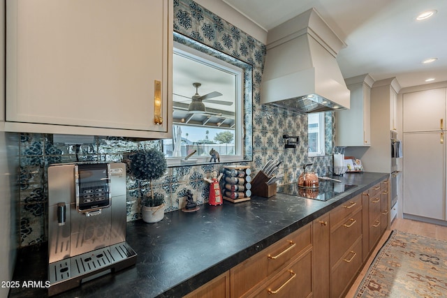 kitchen with black electric stovetop, a ceiling fan, custom range hood, and tasteful backsplash