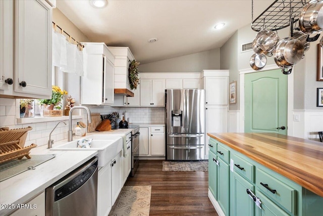 kitchen with green cabinetry, appliances with stainless steel finishes, a sink, white cabinets, and butcher block counters