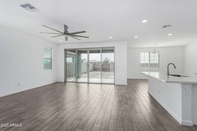 unfurnished living room featuring dark hardwood / wood-style flooring, sink, and ceiling fan with notable chandelier