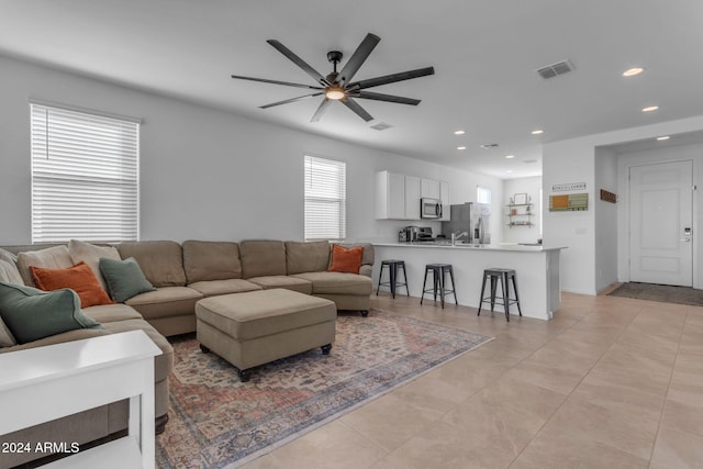 living room with a wealth of natural light, ceiling fan, and light tile patterned floors