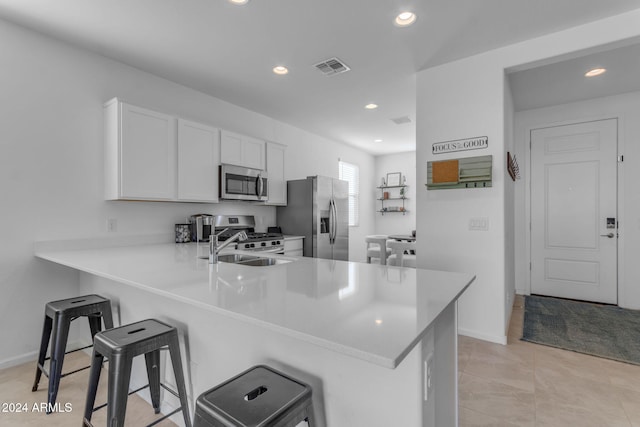 kitchen featuring a breakfast bar area, kitchen peninsula, white cabinetry, and appliances with stainless steel finishes