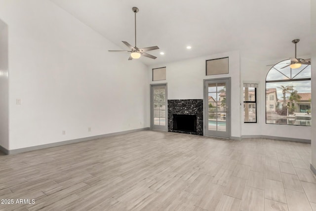 unfurnished living room with baseboards, a fireplace, light wood-style flooring, and a ceiling fan