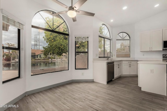 kitchen with a ceiling fan, a sink, stainless steel appliances, light countertops, and light wood-style floors