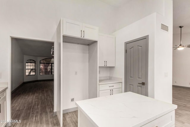 kitchen with light wood finished floors, white cabinetry, and light stone counters