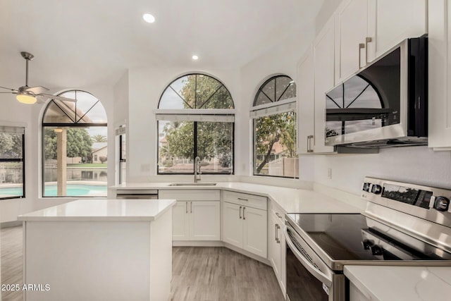 kitchen featuring recessed lighting, a sink, stainless steel appliances, light countertops, and white cabinets