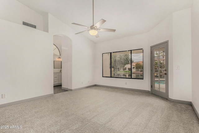 carpeted spare room featuring visible vents, baseboards, ceiling fan, arched walkways, and high vaulted ceiling