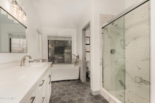 bathroom with tile patterned floors, a freestanding tub, toilet, a marble finish shower, and vanity