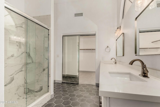 bathroom with a sink, visible vents, a marble finish shower, and tile patterned flooring