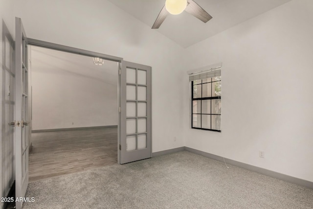 carpeted spare room with french doors, baseboards, a ceiling fan, and vaulted ceiling