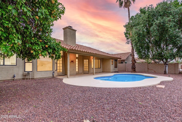 pool at dusk with a patio area, a fenced in pool, and a fenced backyard