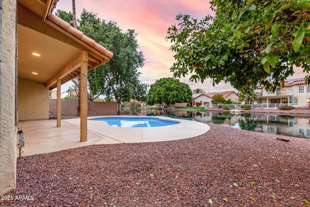 view of swimming pool featuring a fenced in pool, a patio, a fenced backyard, and a water view