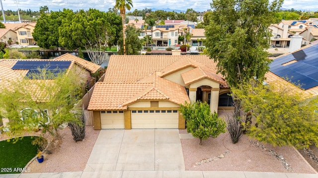 mediterranean / spanish home featuring a garage, a residential view, stucco siding, and a tile roof