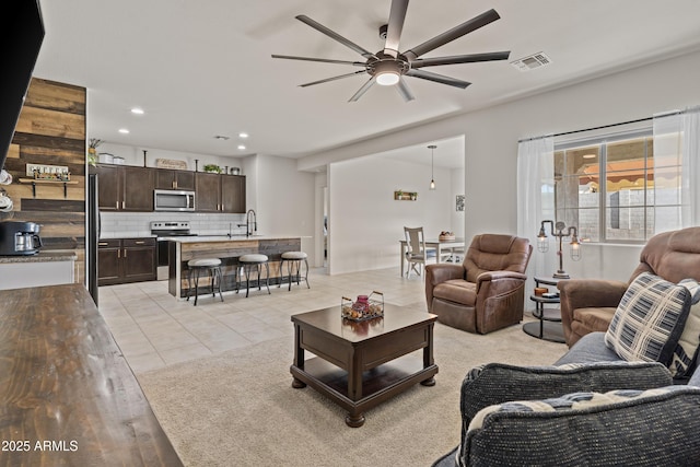 living room with sink, ceiling fan, and light tile patterned floors