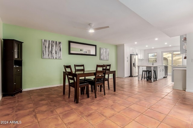 tiled dining room with ceiling fan and sink