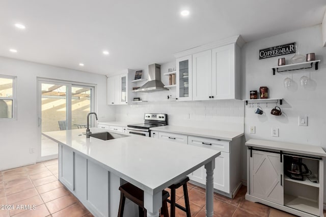 kitchen featuring white cabinets, stainless steel range with electric stovetop, and wall chimney range hood