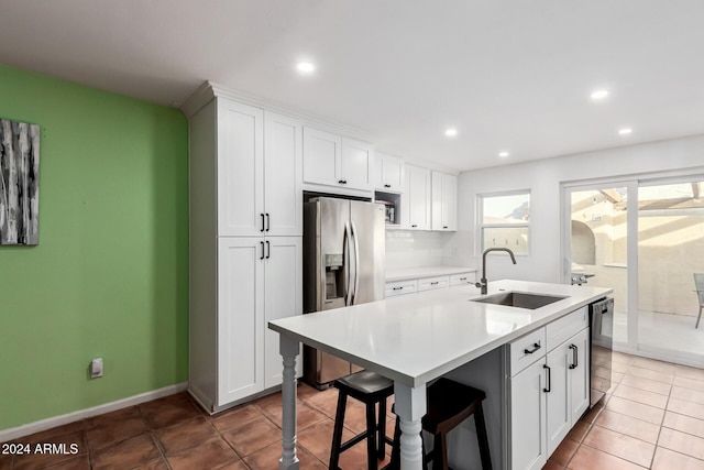 kitchen with white cabinets, appliances with stainless steel finishes, a center island with sink, and sink