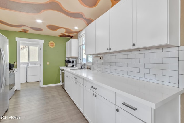 kitchen featuring tasteful backsplash, sink, washer and dryer, light hardwood / wood-style floors, and white cabinetry