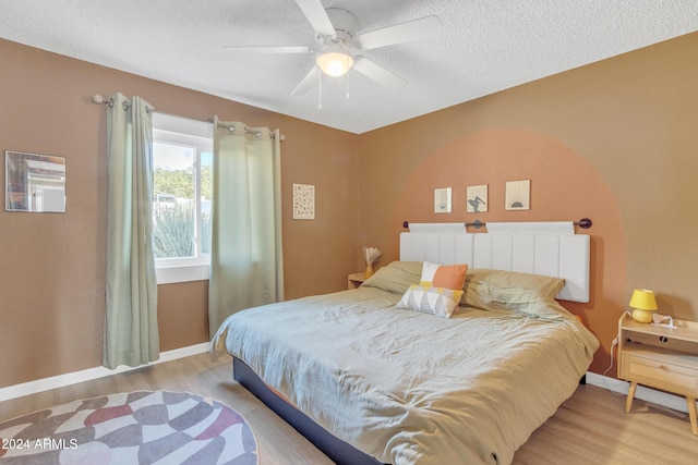 bedroom with ceiling fan, light hardwood / wood-style flooring, and a textured ceiling