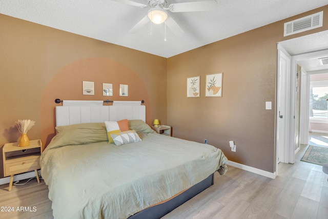 bedroom featuring ceiling fan, light hardwood / wood-style floors, and a textured ceiling