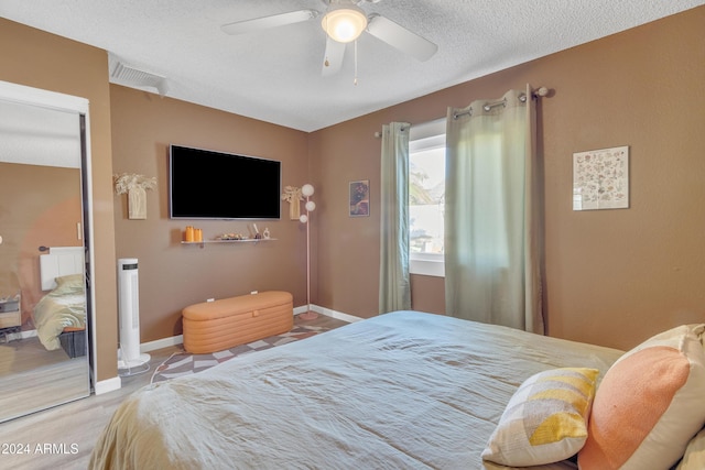 bedroom with hardwood / wood-style floors, a textured ceiling, a closet, and ceiling fan