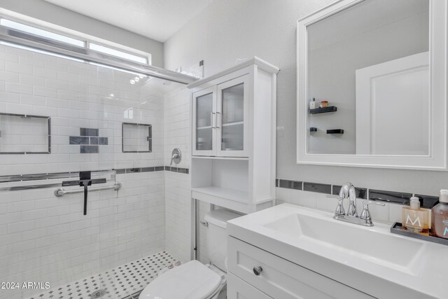 bathroom with a shower with door, vanity, and toilet