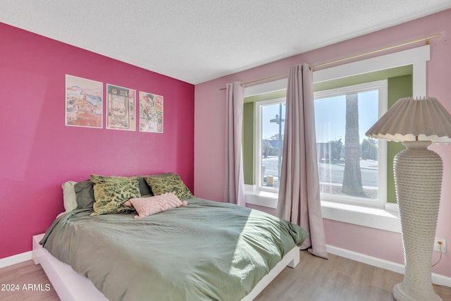 bedroom with light hardwood / wood-style floors and a textured ceiling