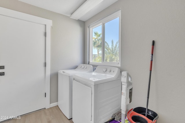 laundry area with washing machine and dryer and light wood-type flooring